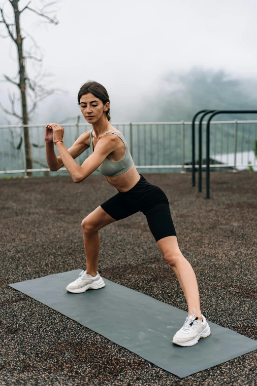 a woman standing on a yoga mat doing stretching exercises