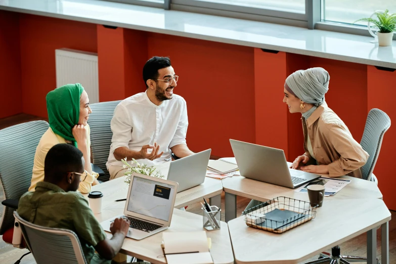 five people talking and laughing around a conference table