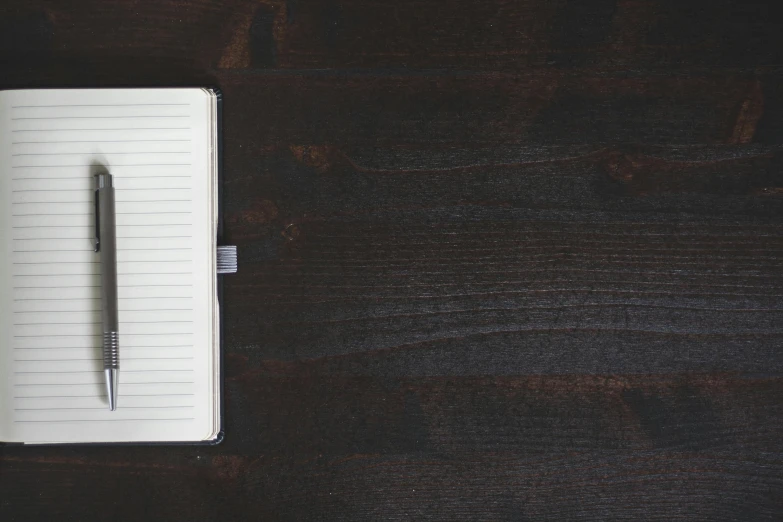 a notepad, pen and some kind of paper on a table