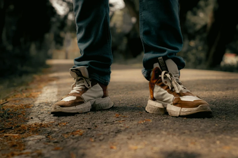 a person wearing sneakers that are on the side of a road