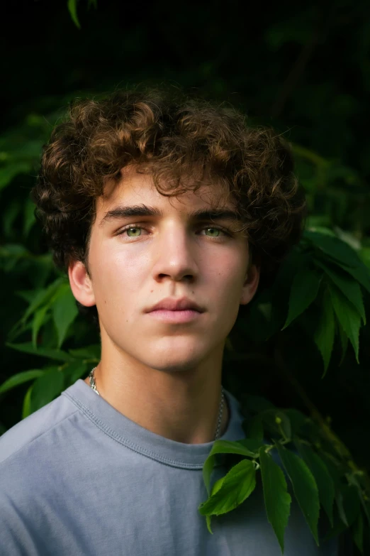 a young man is standing in front of some trees