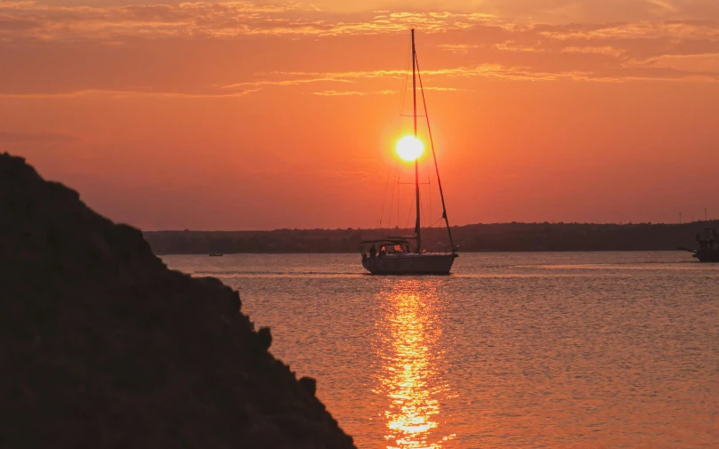 a boat sailing on water at sunset in the background