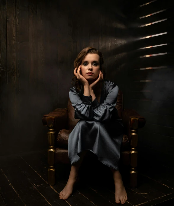 a young woman in a dark room holding her hand on her ear