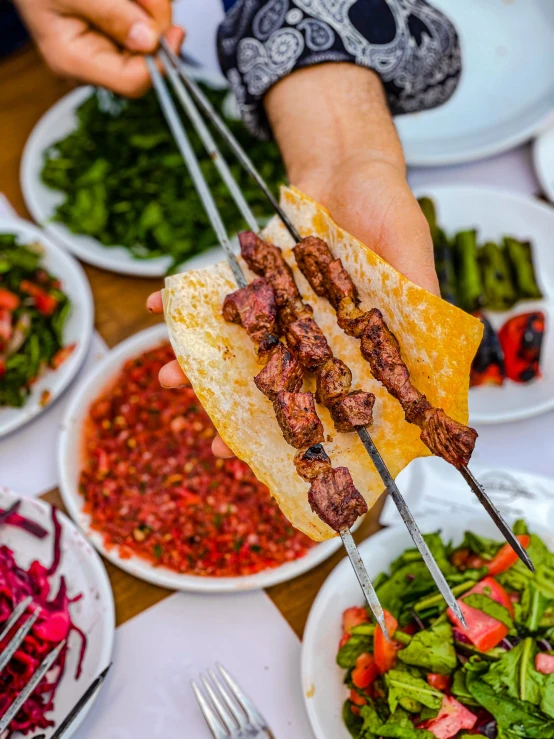 the man is holding a piece of lamb meat and a salad