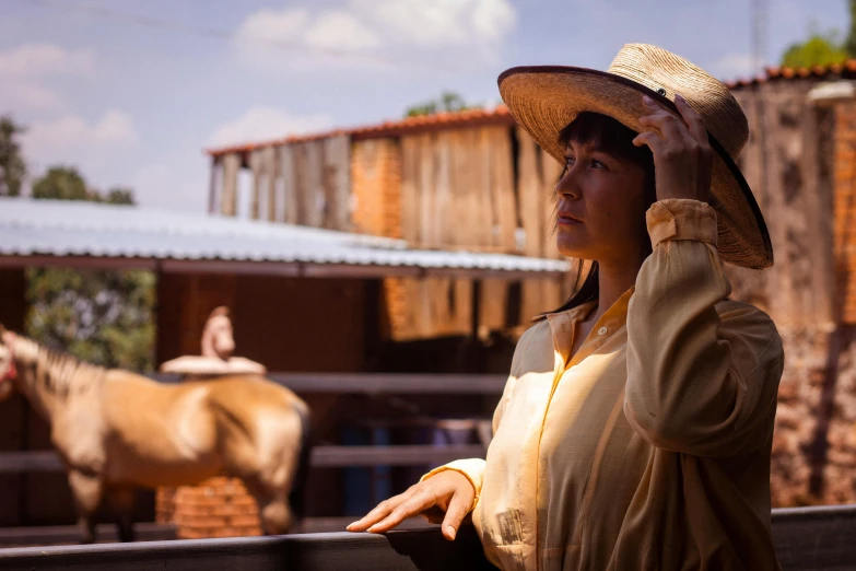 a woman in a hat looks over the fence