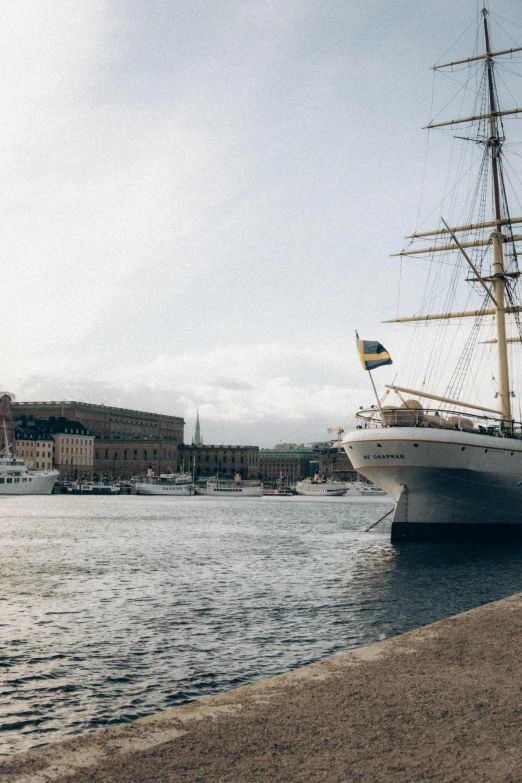 an old sailing boat is docked next to the shore