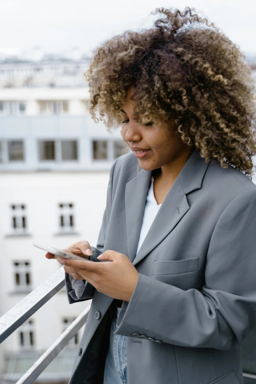 woman in suit standing outside while texting on her phone