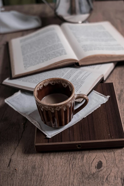 a book sitting on top of a wooden table next to a cup of coffee