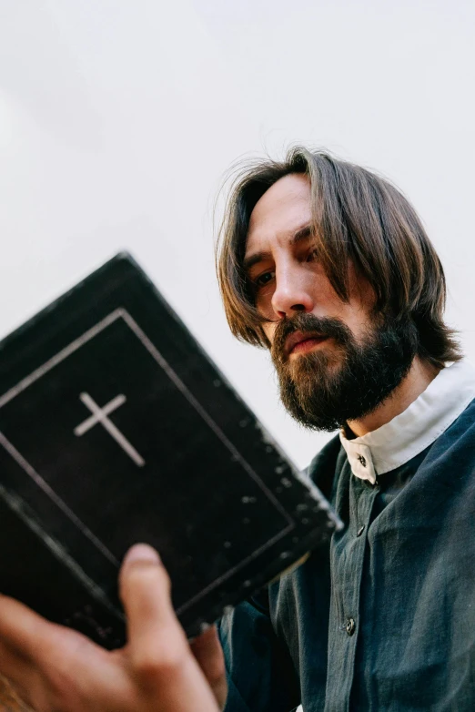 a man reading a book with a cross on it