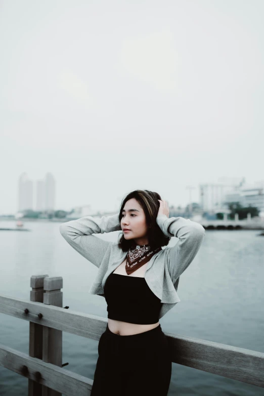 a woman wearing a bandana standing on a rail next to the water