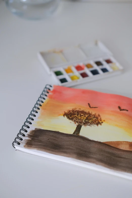 a painting on top of a table near a water bottle and a drawing of a tree