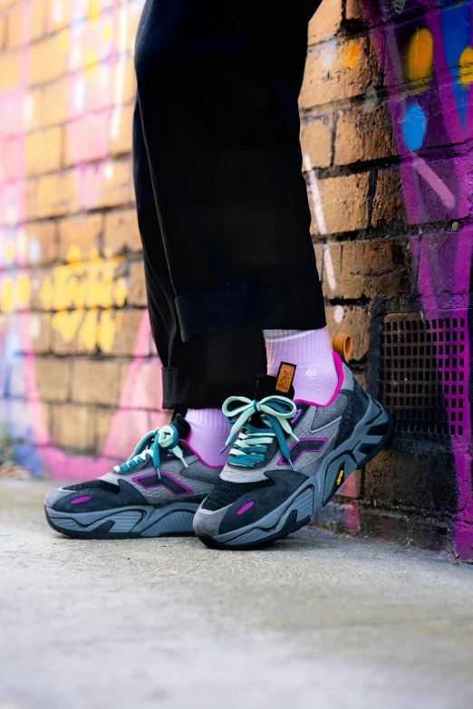 someone standing against a graffiti wall with a black and purple sneaker on