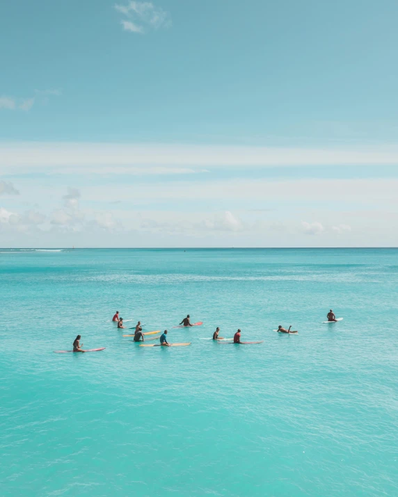 several people paddle on their surfboards in the clear blue waters