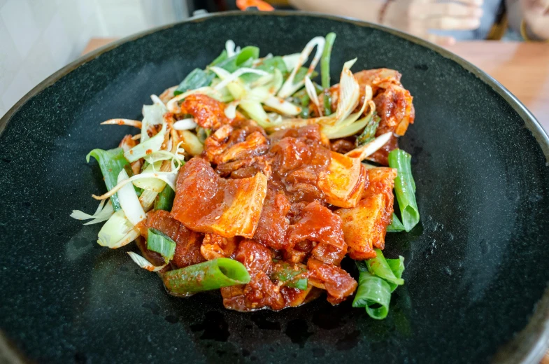 a black plate topped with some green vegetables