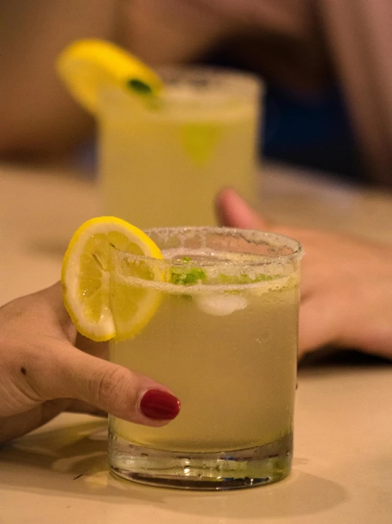 two cocktail glasses with beverages are sitting on a counter