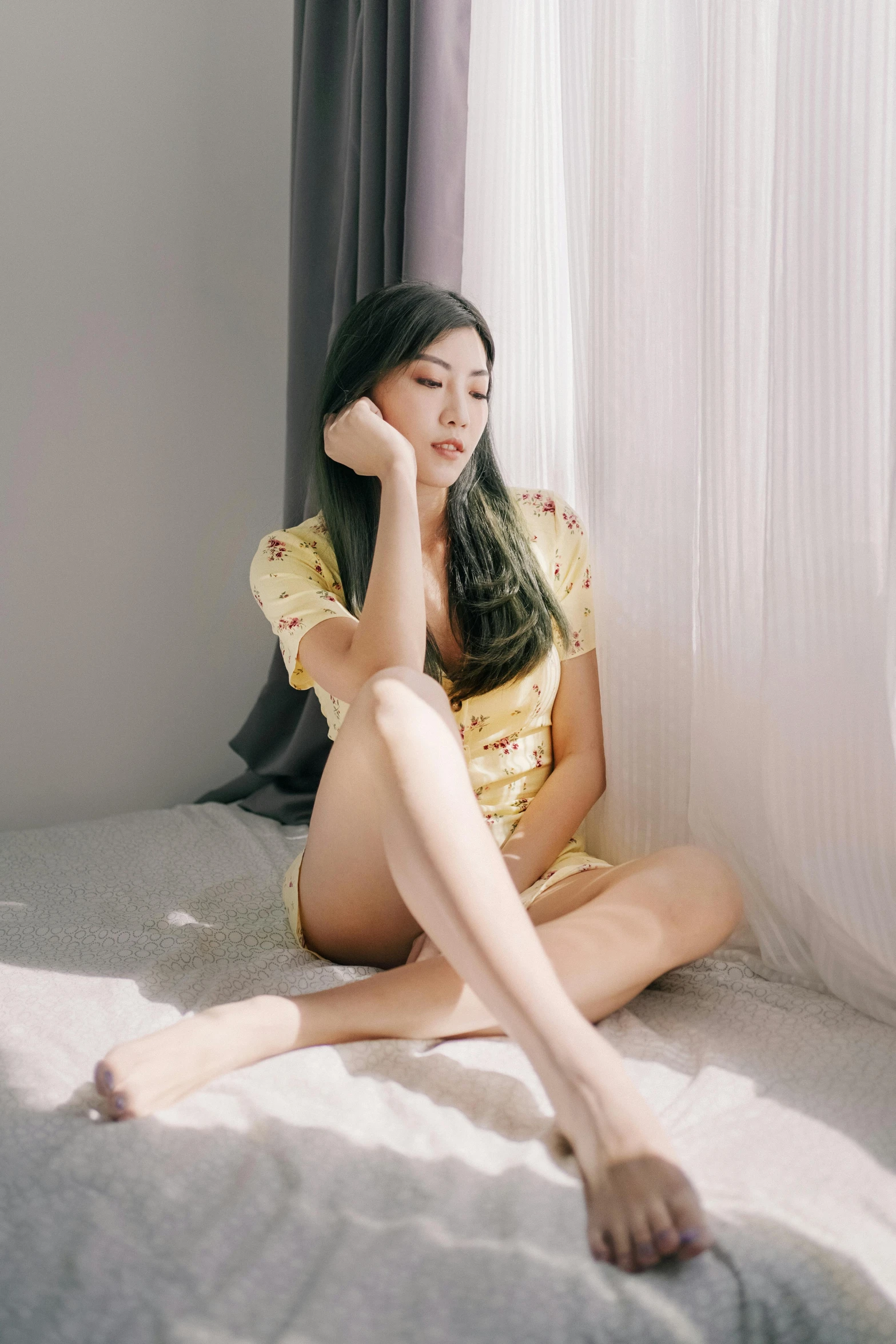 asian woman sitting on a bed in a yellow dress