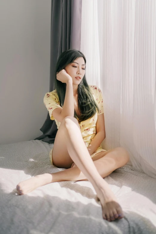 asian woman sitting on a bed in a yellow dress