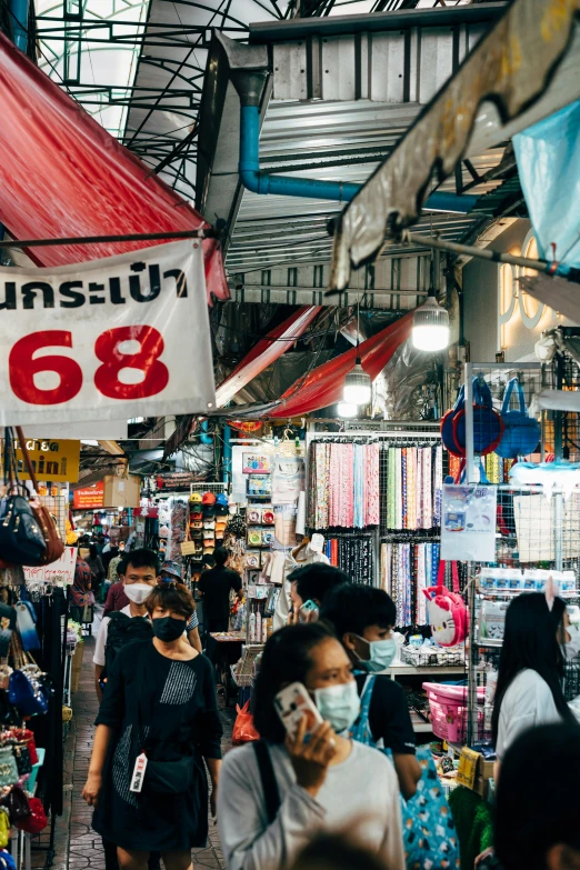 people are walking in a market area with masks