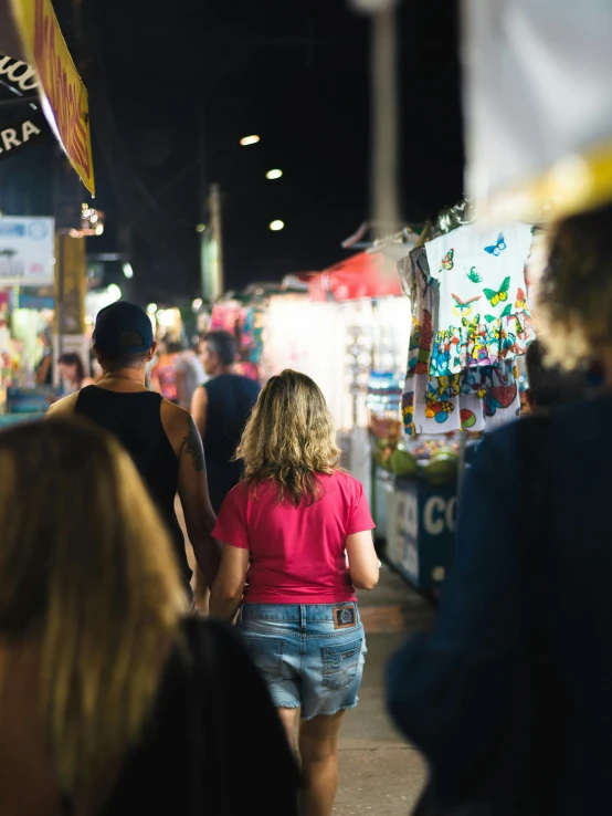 people walk down the sidewalk as they shop at night