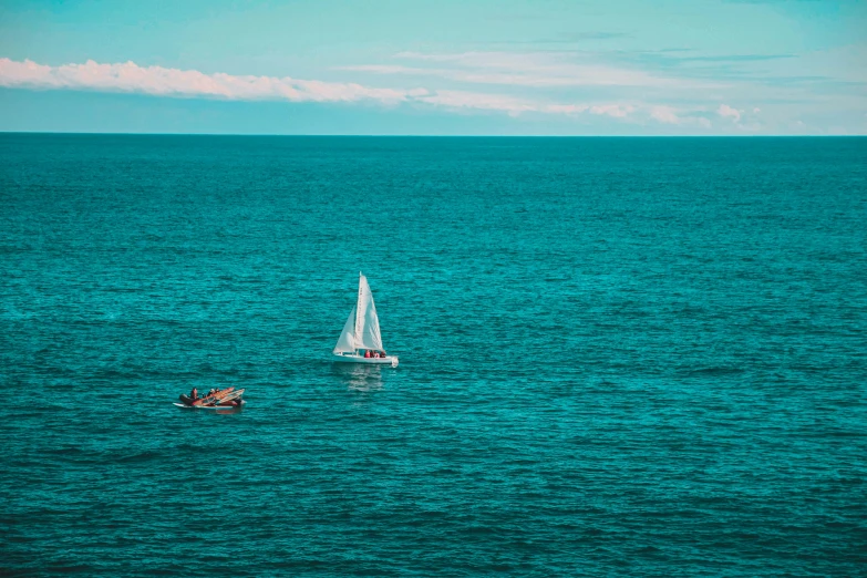 two sail boats sailing through an open sea