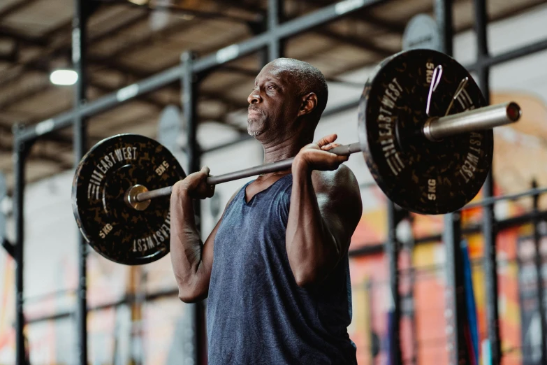 a man lifts a barbell with  on in a gym