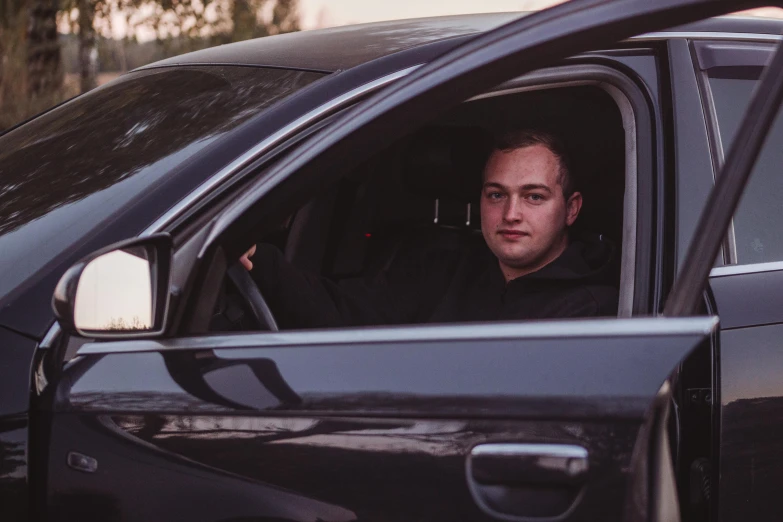 a young man driving a car down a road