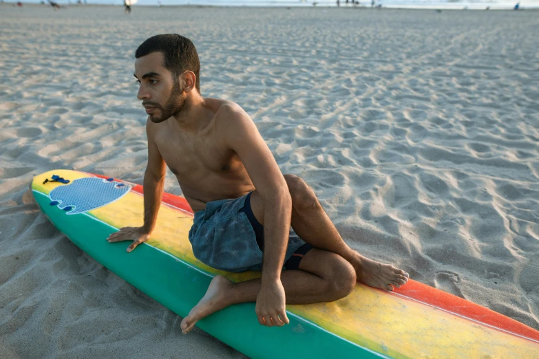 the man sits on his surf board at the beach