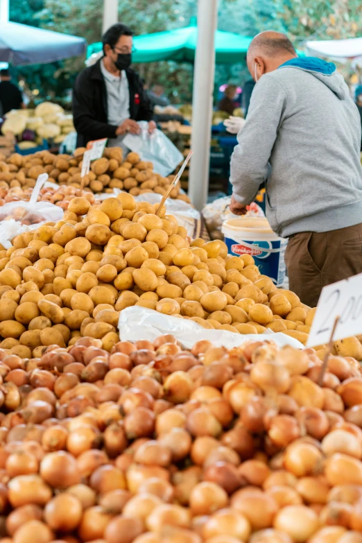 a man is standing over a variety of apples at an open air market