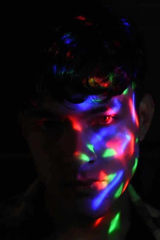 a young man wearing glowing fluorescent colors is in the dark