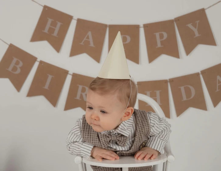a baby in a party hat on a chair