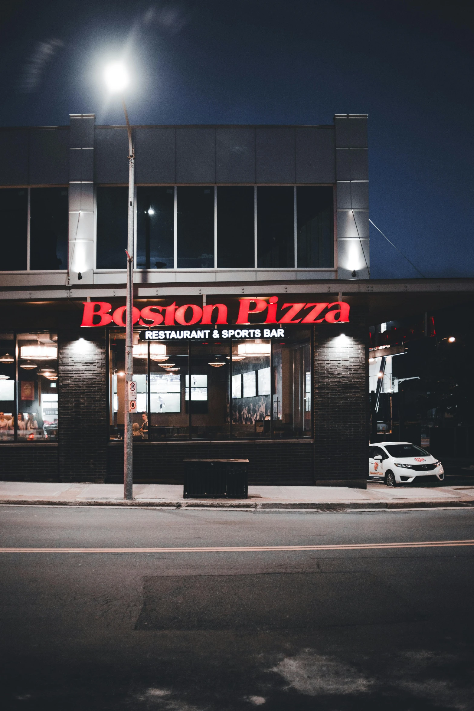 a brick building with a neon sign that reads boston pizza