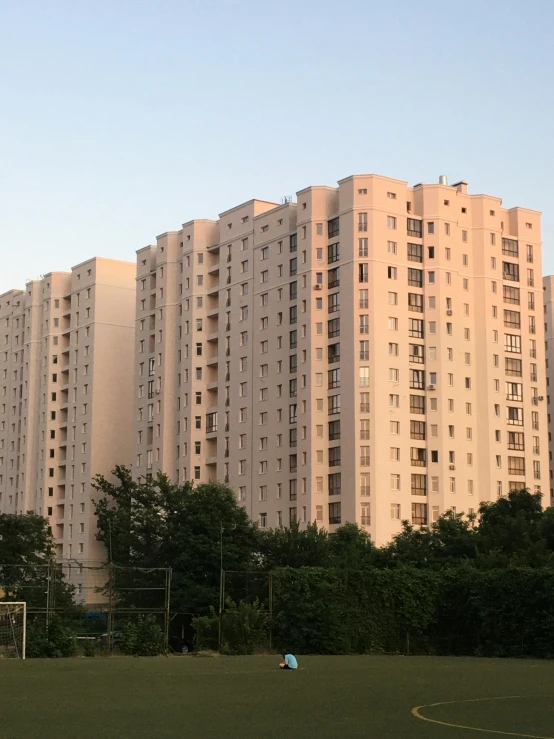 people on a field playing soccer in front of large building