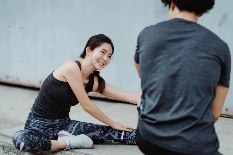 an asian woman holding the ankle of another asian man