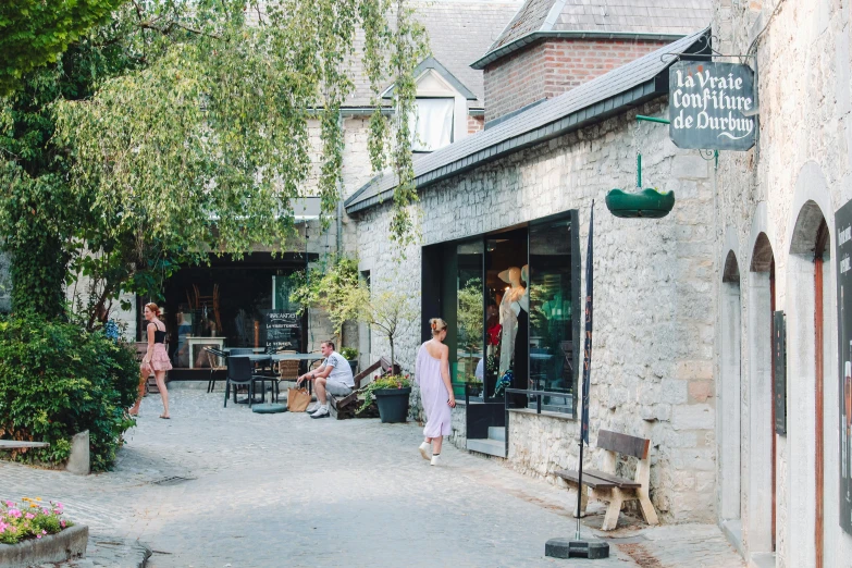 a woman walking down a street past shops and people