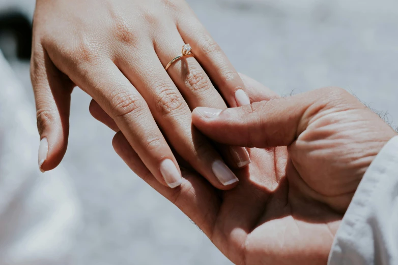 the engagement ring is on top of the hands of the bride