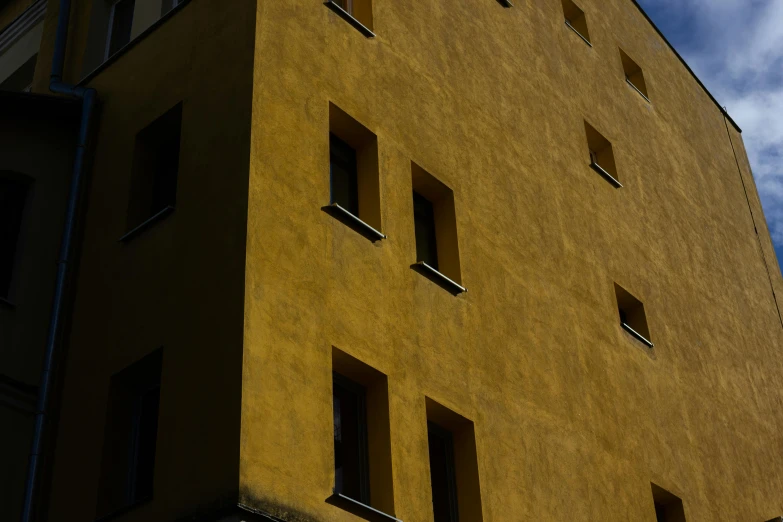 a yellow building with six windows and a sky in the background