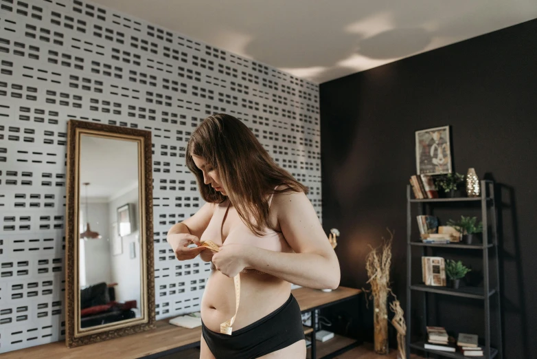 woman without clothes checking her stomach in a room