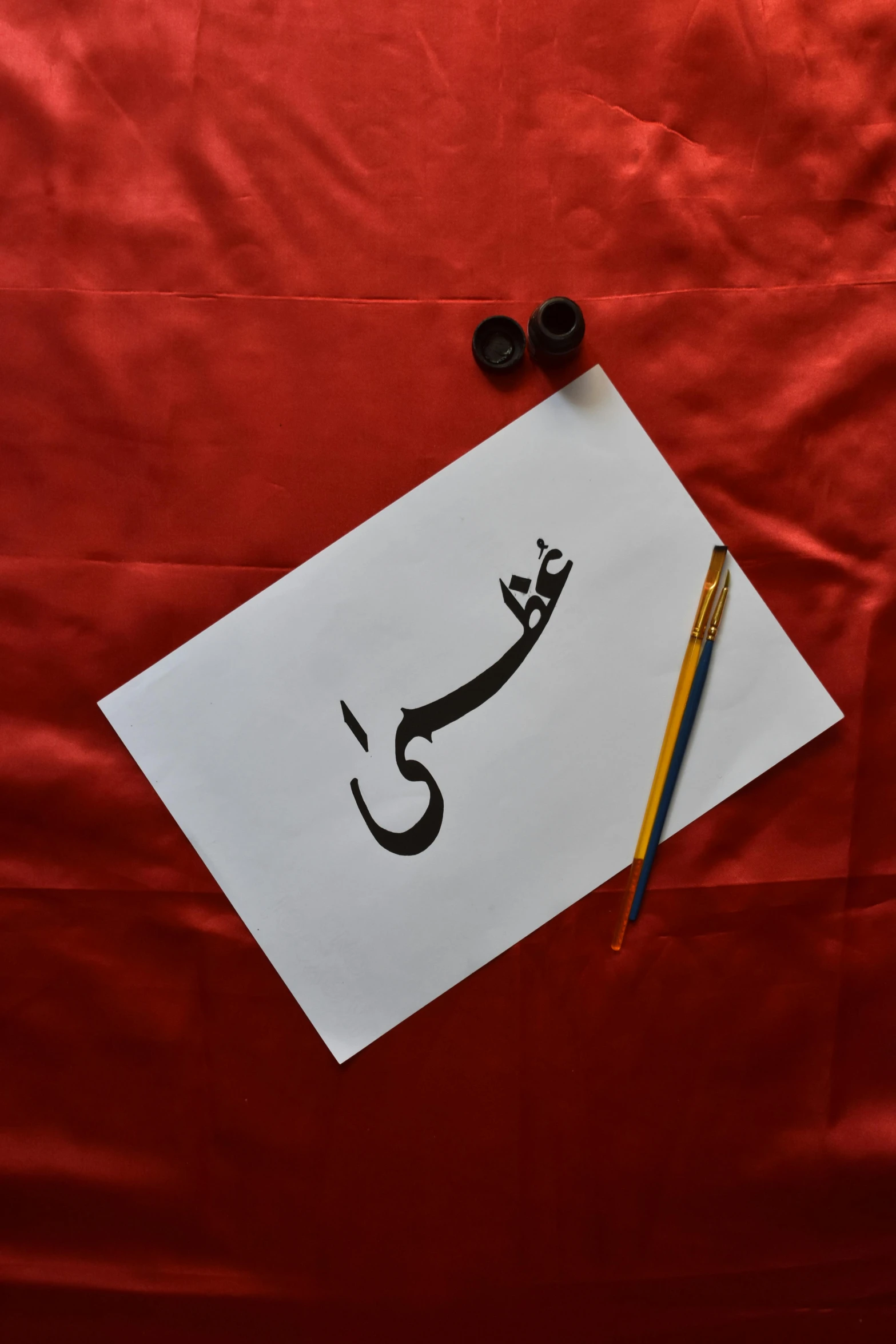 a piece of paper with an arabic writing in it next to two marker pens