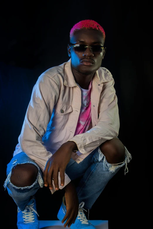 a man in sunglasses and a pink shirt sitting on a table