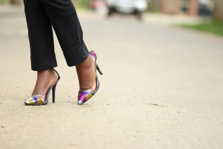 a woman standing on the road wearing colorful heels