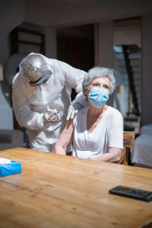 two people in masks standing next to a table