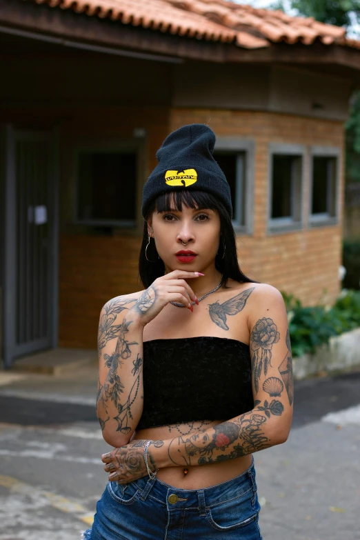 woman with a hat and tattoos poses for the camera