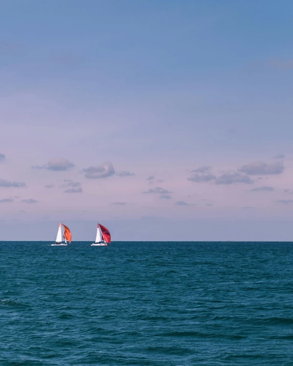 several sailboats sailing across the open ocean on clear day