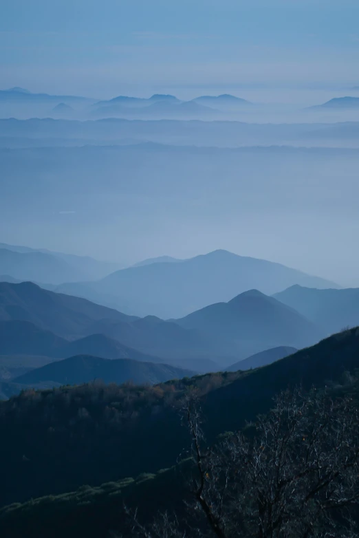 an image of a blue mountains with mist rising from them