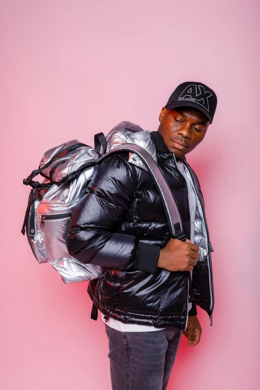 a black man standing and holding onto a large metal backpack