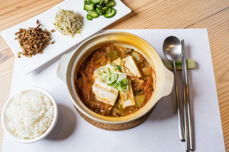 an open bowl with soup and spoons on a white placemat