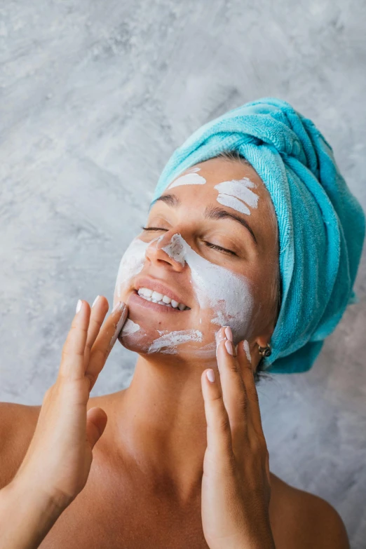 a woman wearing a towel on top of her head putting sha on her face