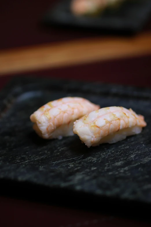 some shrimp on a black plate with chopsticks