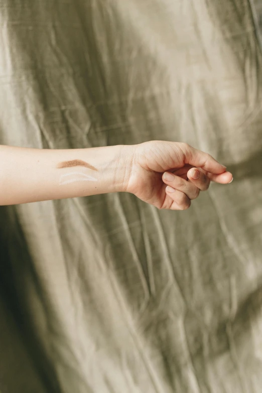 a womans hand reaching for soing that is on her arm