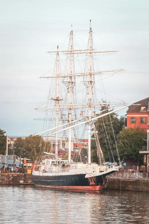 a sail boat docked near some red brick buildings